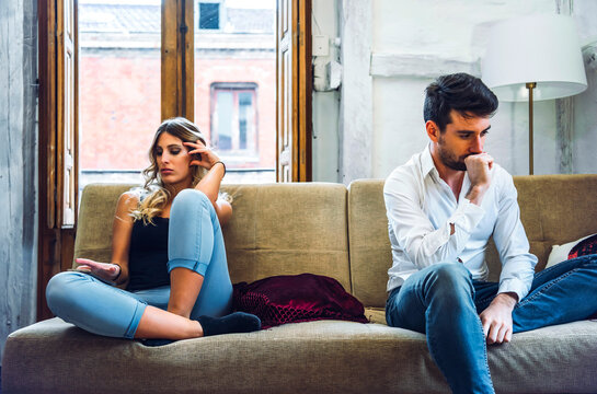 Couple sitting on sofa apart and being angry after quarrel