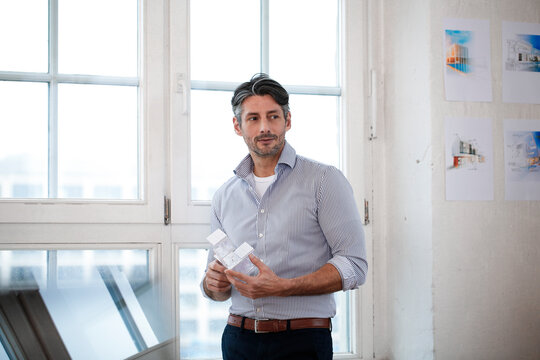 Man in office holding architectural model