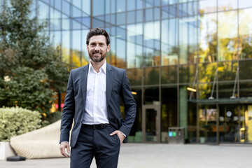 Professional male entrepreneur smiling at camera, standing outdoors in business district,...