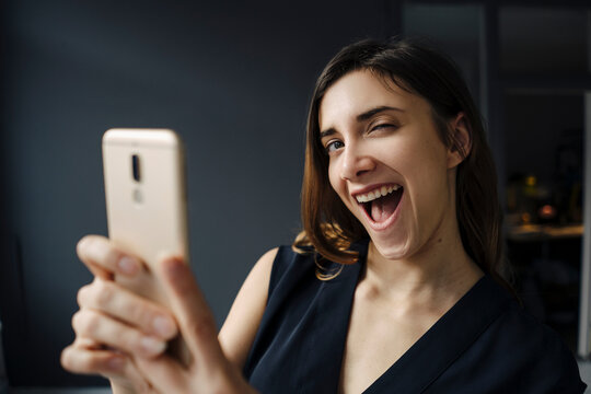 Portrait of young woman with smartphone pulling funny faces