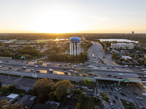 Aerial view of the water tower rising above the highway, with the sunset casting long shadows over the urban landscape, Sunrise, Florida, United States.