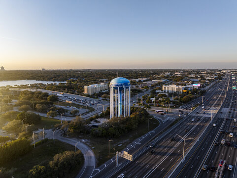 Aerial view of a water tower standing tall amidst a tapestry of urban sprawl, contrasting the azure sky with the city's vibrant hues, Hollywood, Florida, United States.