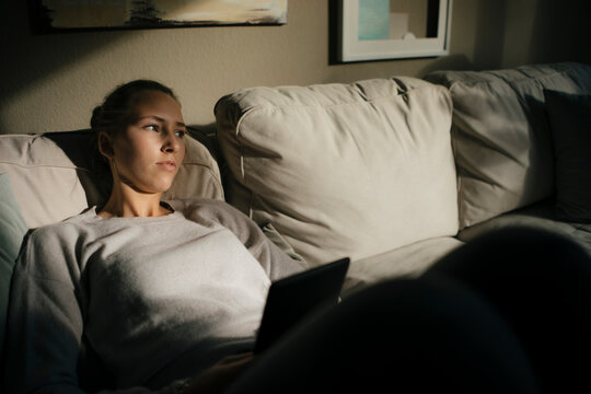 Serious teenage girl with tablet sitting on couch at home