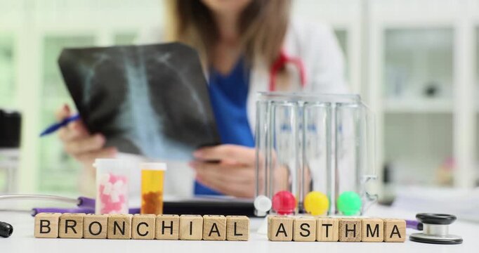 Wooden blocks spell words Bronchial Asthma near x-ray film and test tubes. Doctor reviews lung image marking notes for breathing plan in clinic