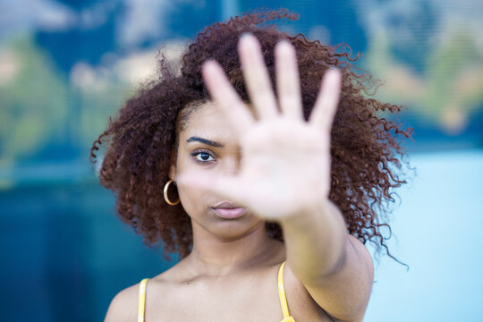 Close-up of young woman showing stop sign