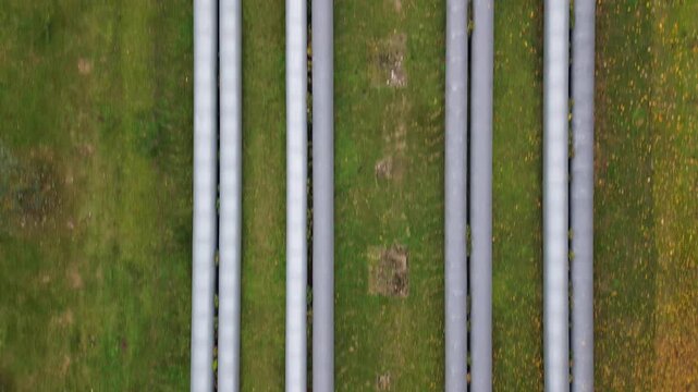 Aerial view of oil and gas pipelines stretching across green landscape, showcasing the intricate layout and connection of infrastructure, camera gradually zooms out to reveal surroundings