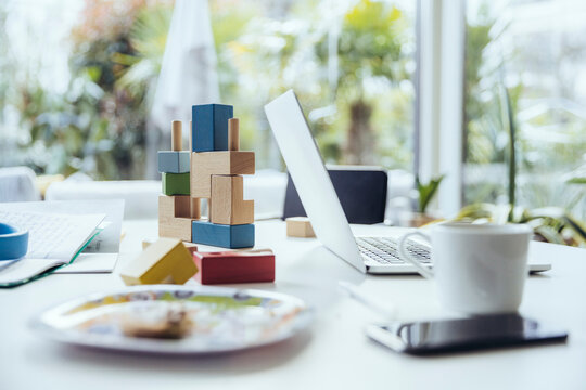 Laptop on dining table with building blocks and dishes