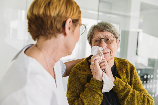 Doctor?s assistant comforting sad senior patient in medical practice