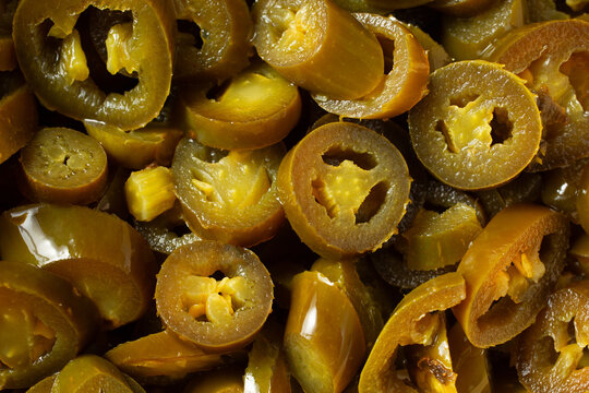A top down view of a pile of canned jalapeno slices, as a background.