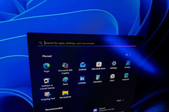 Windows 11 Start menu displaying pinned applications and search bar against a blue abstract background, modern operating system user interface and software navigation concept