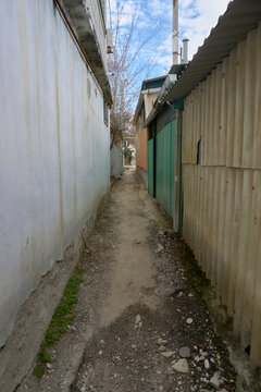 &laquo;Slum alleyway: narrow path between weathered walls and garages&raquo;.alley, slum, passage, corridor, backstreet, narrow, confined, utilitarian, dilapidated, weathered, worn, grim, squalid, desolate, aban