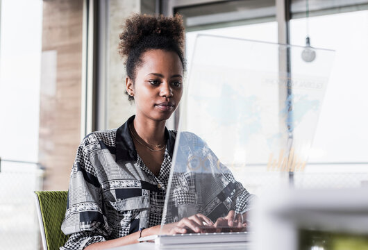 Young woman working in office using transparent computer