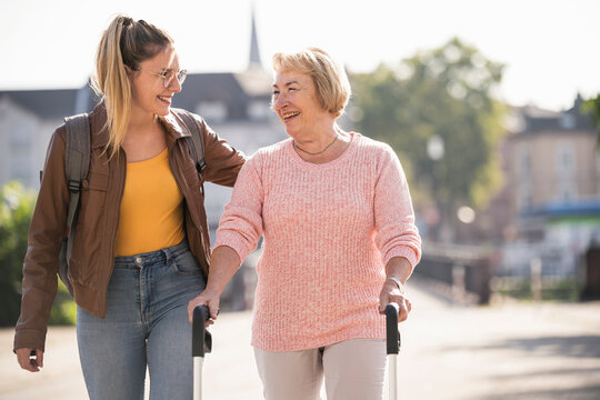 Granddaughter assisting her grandmother walking with wheeled walker