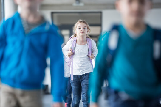 Group of schoolgirls walking out of school building after a day of learning and socializing with classmates.