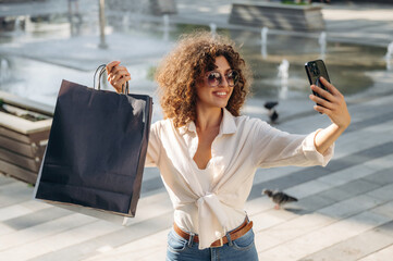 Selfie time. Happy woman is with shopping bags in town