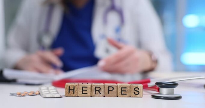 Wooden blocks spell word Herpes near stethoscope and pills on clinic desk. Female doctor reviews lab result sheet writing plan for outbreak control
