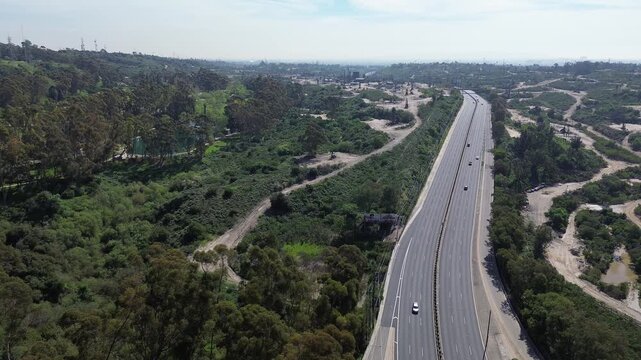 Hillside oil infrastructure at Baldwin Hills ridgeline overlooks active well pads and looping service roads by Kenneth Hahn State Recreation Area. Mixed grasses, terraced cuts in Los Angeles, CA