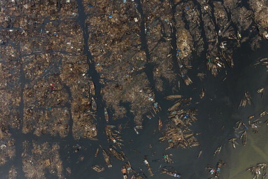 Aerial view of canoes and boats navigating the waterways amidst floating debris, creating a stark contrast between nature and pollution, Lagos, Lagos, Nigeria.