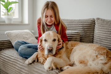 Teen Girl Playing With A Golden Retriever Dog On The Sofa