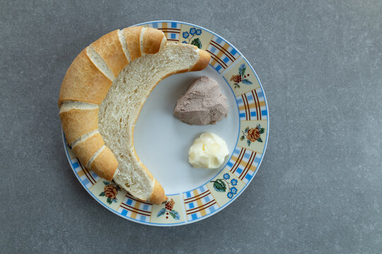 Crescent roll cut lengthwise with butter and liver p&acirc;t&eacute; on plate