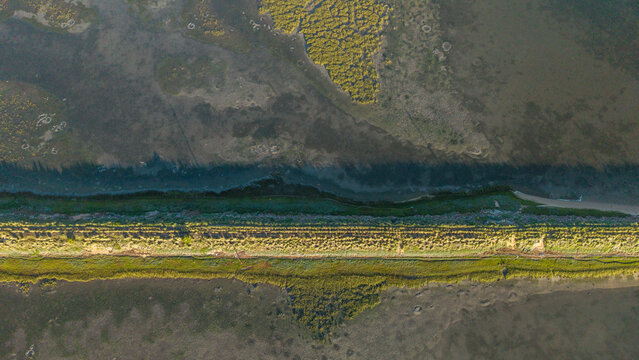 Aerial view of the contrasting textures of the mudflats and marshlands, divided by a green strip of land, Knysna, South Africa.