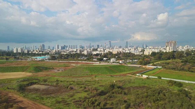Ariel Sharon Park construction zone set against the modern skyline of Tel Aviv and the city's southern high-rise district.