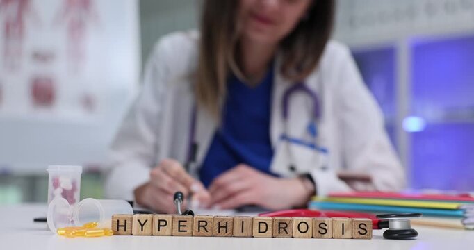 Wooden cubes on desk form medical term Hyperhidrosis. Female doctor studies test results of patient carefully to determine accurate diagnosis