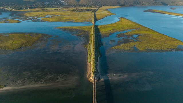 Aerial view of a strip of land dividing the tranquil waters, a serene blend of blue and green, where nature's artistry paints a vivid landscape, Knysna, Western Cape, South Africa.