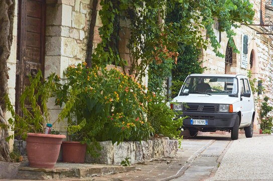 Front view of a white vintage Fiat Panda parked in a narrow stone street of a medieval village, Spello, Umbria, Italy, Europe