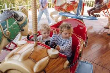 A girl and a boy ride on a carousel, in a car. Happy kids © standret