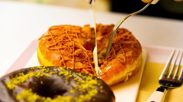 Cutting Dubai-style donuts with chocolate glaze, topped with chopped pistachios