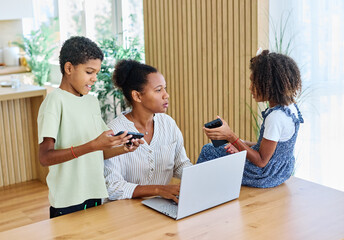 Fototapeta premium Portrait of ayoung businesswoman working on laptop from home distracted by surrounding noisy children. Motherhood, childhood, family, freelance job, home office concept