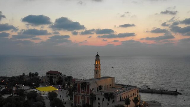 Aerial view of St. Peters Church bell tower in Old Jaffa overlooking the Mediterranean sea and Tel Aviv city skyline at sunset