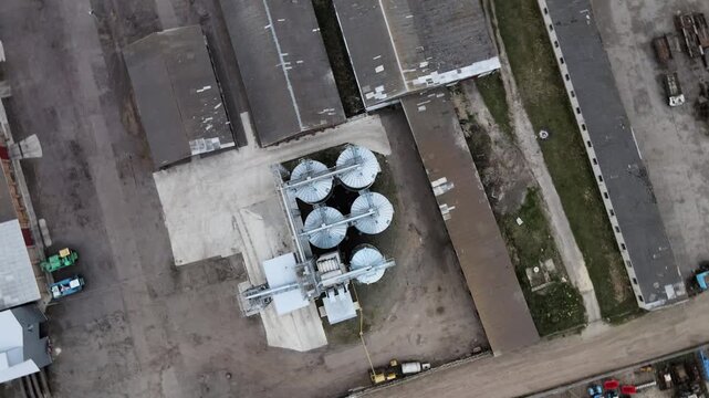 Aerial drone view of agricultural silos, grain elevators and farm buildings spinning in a top down shot