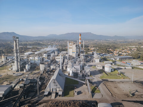 Aerial view of the DS Smith paper mill industrial complex with towering chimneys piercing the skyline, a stark contrast against the backdrop of distant mountains, Deocriste, Portugal.
