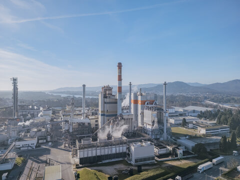 Aerial view of a sprawling DS Smith Paper mill industrial complex with tall chimneys piercing the clear blue sky, the whole scene bathed in the soft glow of daylight, Deocriste, Portugal.