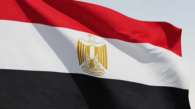 Closeup of the national flag of Egypt waving gently in the wind against a clear sky showcasing the iconic eagle emblem in the center.