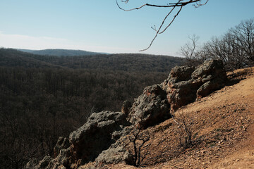 Rock formations at Orlove Stene viewpoint in Fruska Gora, Serbia overlooking a vast forest valley. Rugged terrain and clear sky highlight adventure and nature travel themes © Ekaterina