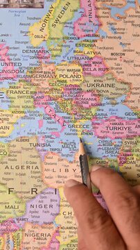 male hand pointing to Athens Greece on world map, European city and travel concept - vertical above-view footage