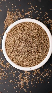 Top View of Carom Seeds (Ajwain) in White Bowl on Black Background &ndash; Rotating Vertical Footage