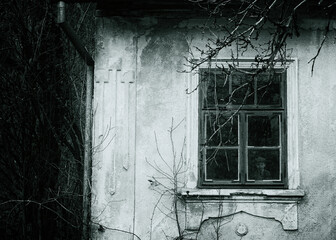 Chilling horror scene oif haunted house. Spooky little boy appears behind an old wooden window.
