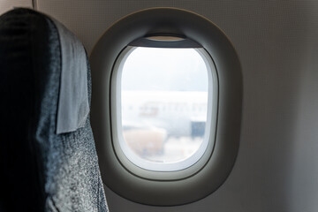 Naklejka premium The interior of a modern airplane cabin features a clean window and a textured grey fabric seat for passenger comfort.