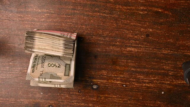 Top View Close-Up of a Man Placing 500/- Currency Note Bundles on Wooden Table &ndash; Finance Footage