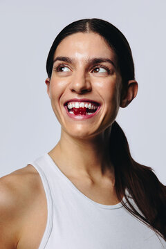 Young woman biting a gummy in studio