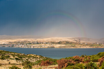 Pag island town with rainbow over arid landscape