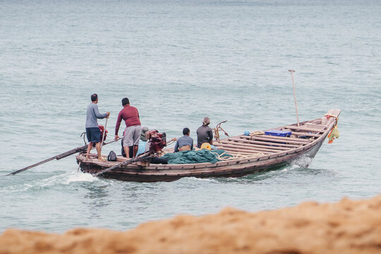 Traditional Thai Asian fishing boat with fishermen on a coastal fishing trip in the afternoon. The scene of daily fishing work is probably returning from fishing or going to sea.