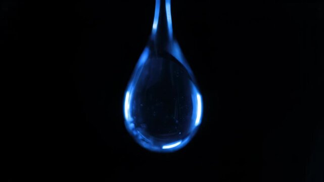 A single blue water drop on a black background with a glowing effect 4k video, animated