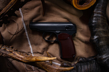 Black semi-automatic pistol on textured brown fabric background, moody cinematic lighting, military style flat lay