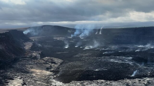 Static 4K view of Kīlauea crater showing numerous steam vents rising from dark lava fields, revealing widespread geothermal volcanic activity.