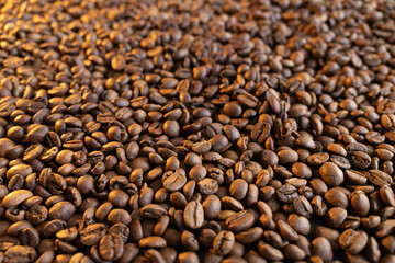Fototapeta premium Close-up macro shot of roasted coffee beans with warm lighting creating a rich texture
